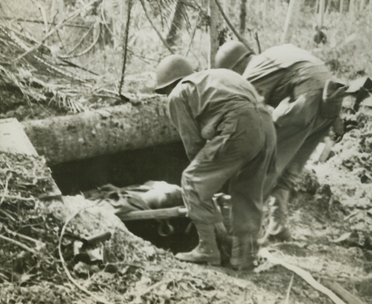 Shelter for Wounded, 12/28/1943. Arawe, N.B. – An American soldier, wounded in the invasion of New Britain, is lowered on a stretcher into a Japanese dougout for protection against the possible return of Nipponese planes. Credit (ACME);