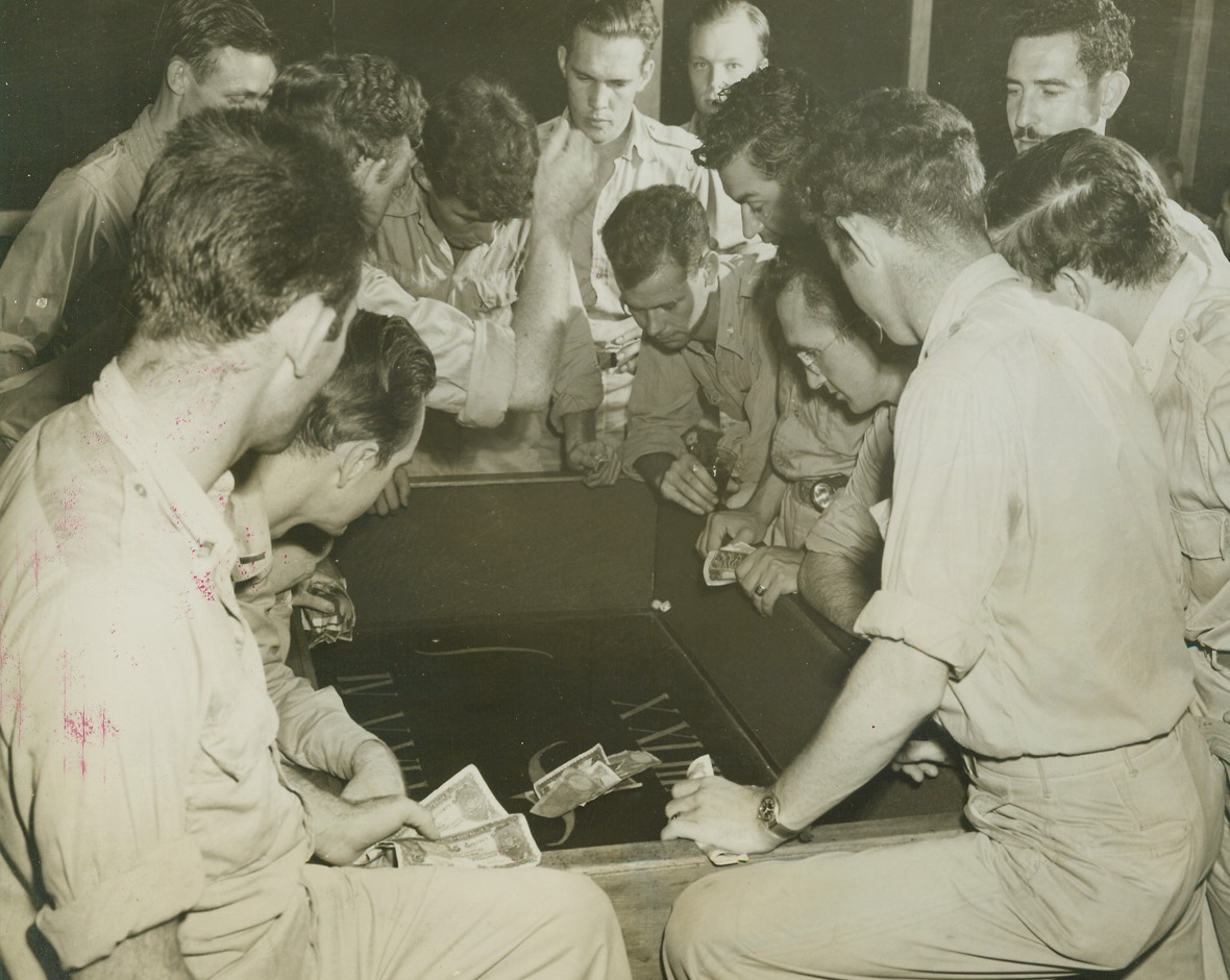 FUN FOR THEIR MONEY, 12/10/1943. NEW GUINEA—Gambling is most definitely “legal” on New Guinea, and Club Six Four, elegant officers’ club belonging to members of an advanced 5th. Air Force bombing unit even has its own gambling room. Soldiers crowd close around the dice table. Ready to win—or lose—some of their Army pay. Credit: ACME PHOTO BY THOMAS L. SHAFER, WAR POOL CORRESPONDENT.;