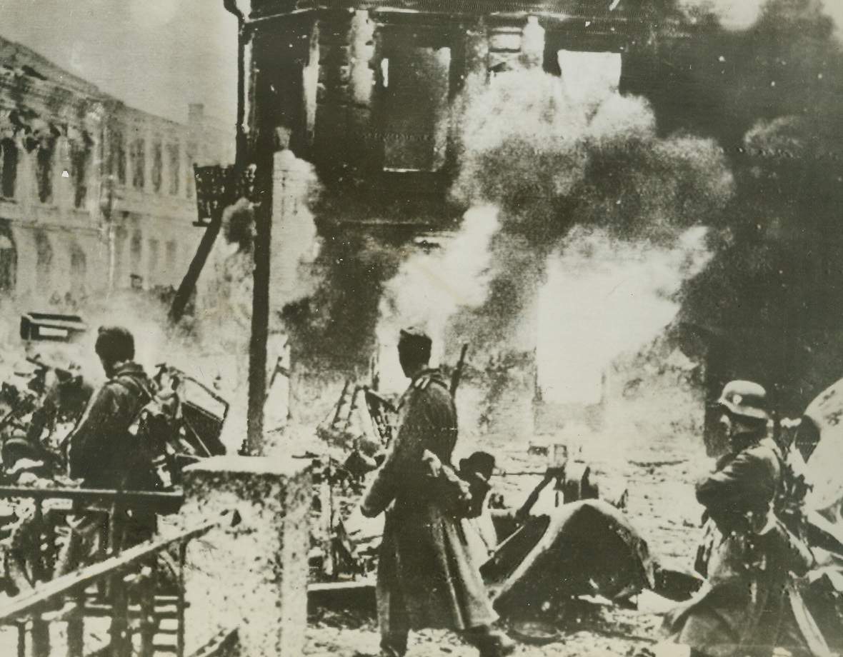Nazis on the Run, 12/30/1943. Somewhere in the U.S.S.R. – Retreating, on the double, through a Russian town in the Kiev sector, these Nazi soldiers watch the village burn as they walk past. The entire town was systematically destroyed by the beaten Germans. Photo was radioed to London from a neutral source.Credit: ACME;