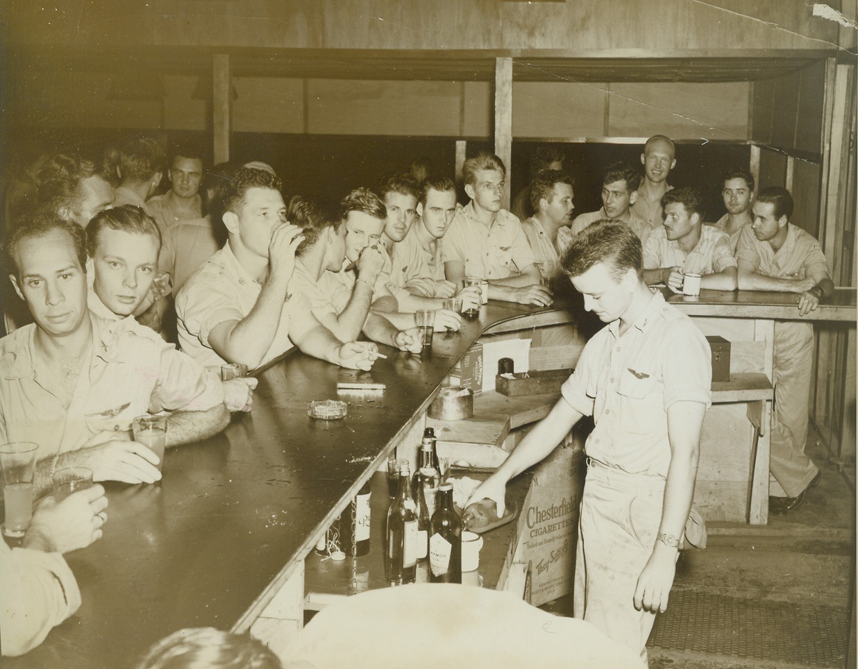 A Dream Come True, 12/20/1943. New Guinea – Officers of an advanced bombing unit of the 5th Air Force labored hard in their spare time, and out of salvaged materials constructed the most elegant club on New Guinea which boasts this long bar.  They surpassed their goal of creating a club worthy of the good old U.S. Credit (ACME photo by Thomas L. Shafer, War Pool correspondent);