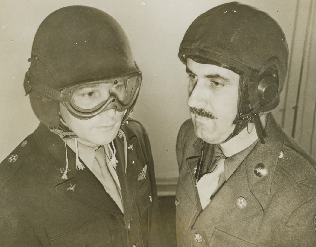 Helmets For Protection, 12/31/1943. Major Edward F. Sustrick (left) of Denver, Colo., and Sgt. William Lyon of Los Angeles, Calif., wear the M3 and M4, helmets designed to protect airmen from low-velocity fragments of anti-aircraft shells. The M3 (left) is of a one-piece type, with hinged flaps, that can be worn by most airmen. The M4 was developed for gunners, who have only limited space in their turrets.;