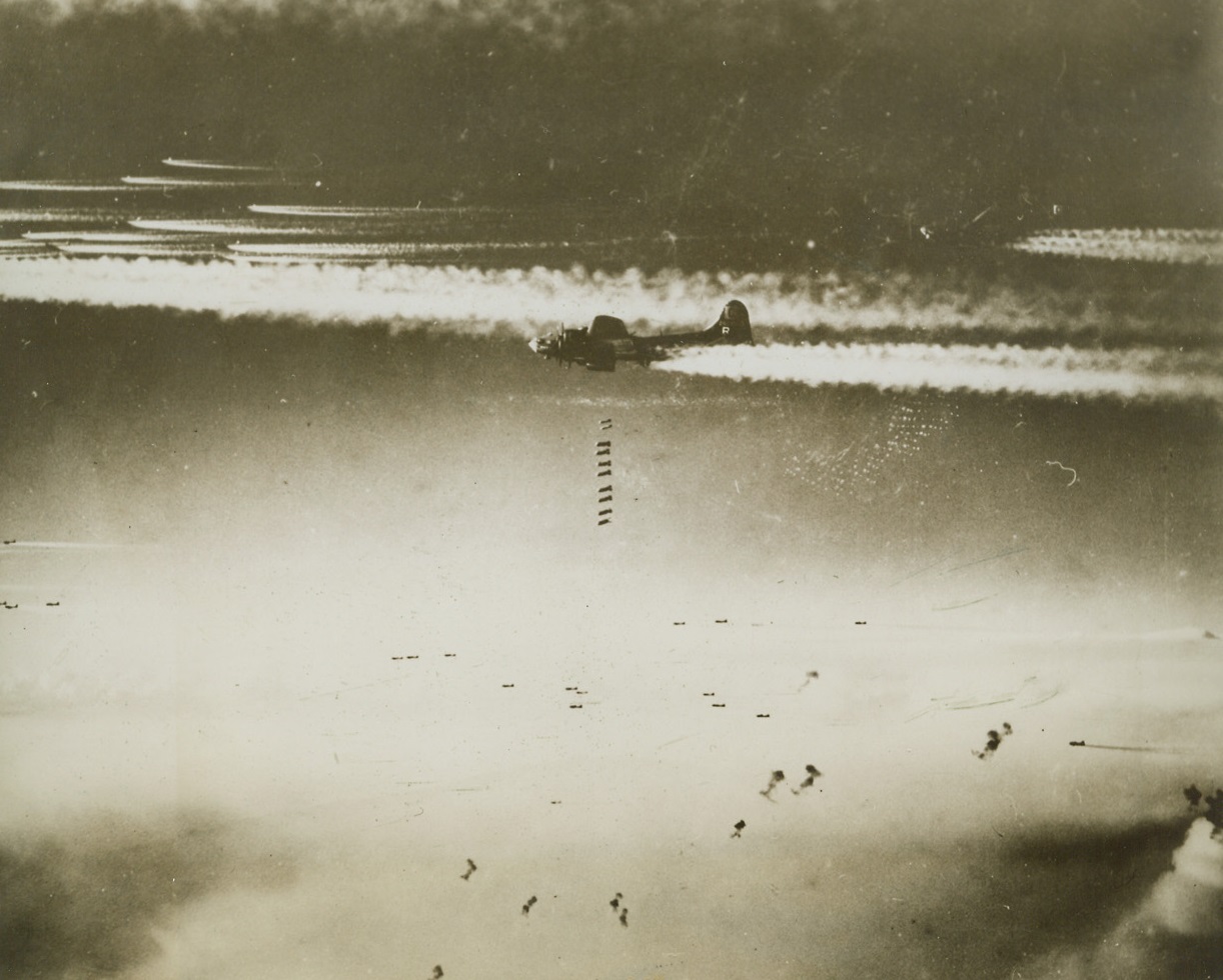Yank “Calling Cards” For Bremen, 12/15/1943. Washington, D.C. – A stick of ten heavy bombs drops from a Flying Fortress of the U.S. Army Air Forces, in the center of this photo, just released in Washington. Exploding anti-aircraft shells, (bottom, center), and vapor trails, (top) can be seen in the photo which was taken during the heavy all-American 1,000 plane raid on Bremen, Germany, last Nov. 26, during the week when Allied Bombers were blasting Berlin to bits. Credit: U.S. Army Air Forces photo from ACME;