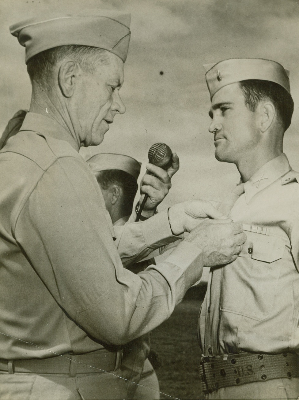 No Title. 12/29/1943. First Lieut. Thomas D. Hindmen, May, Tex., receives the Silver Star decoration for gallantry in action from Maj. Gen. Charles H. Corlett. His mother lives in May, Texas, where the lieutenant was born. His wife, Mary, lives at Carmel, Calif.;