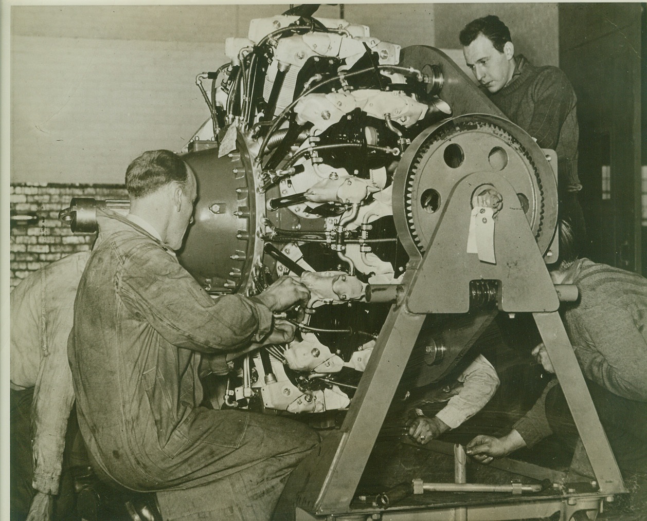 BUILDING ENGINES FOR WAR PLANES, 1/30/1942. MELROSE PARK, ILL.—Aircraft engine production at the Buick Aviation Engine Plant at Melrose Park, ILL., has exceeded its proposed schedules and is gaining acceleration everyday in out-put volume. With several thousand employees at work on assembly lines turning out engines for American bombers and fighter planes, the plant is expected to build most of the aircraft motors for the arms program. This photo, approved by the War Department, is one of the first to be taken inside the plant showing actual production. PHOTO SHOWS: Engine for a bombing plane, fresh from the assembly line, being tuned by mechanics before final test run. Credit: OWI Radiophoto from ACME;