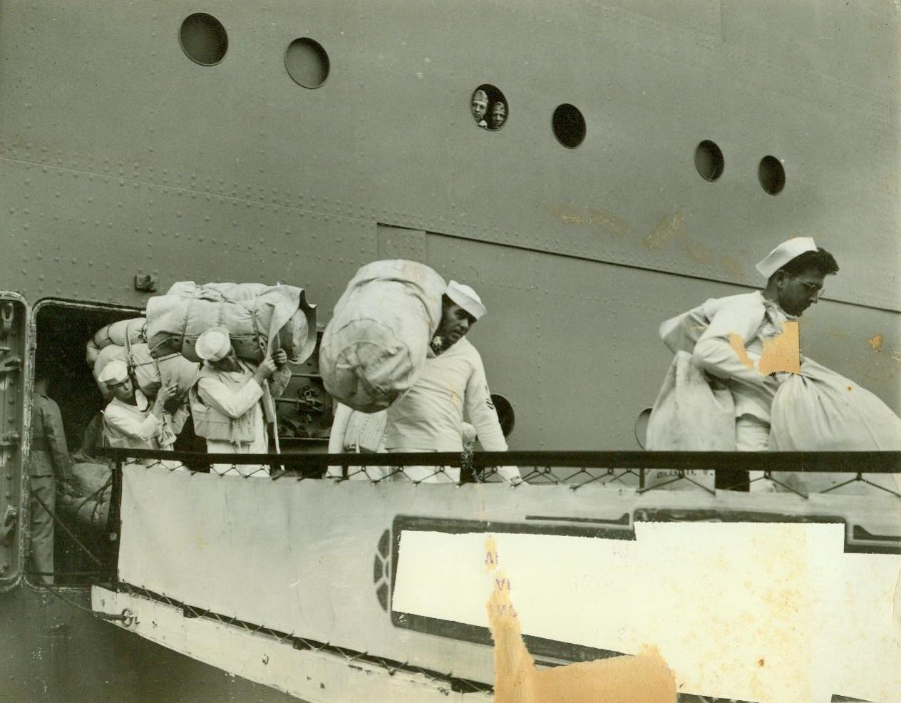 Bound for shore at an American Pacific outpost, 1/3/1942. SOMEWHERE-IN-THE-PACIFIC – Carrying their sea-bags, U.S. sailors go down the gangplank at an American possession in the Pacific, where they are arrived to support forces under attack by the Japanese. Behind them a soldier waits to descend. Passed by U.S. Navy Censor, these are the first pictures to be brought back showing a U.S. troop convoy Pacific-bound. CREDIT LINE (ACME) 1-3-42;