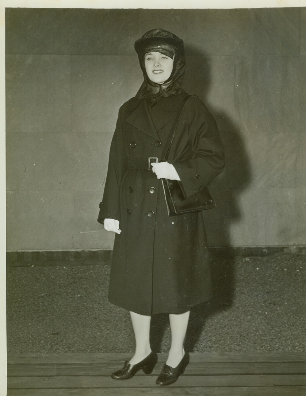 Uniform of Enlisted Wave, 10/1/1942. NEW YORK – Mainbocher designed this navy blue rain outfit that keeps its enlisted wearer as snug against the rains as her commanding officer in the WAVES. Underneath, the Navy enlistee wears a uniform designed like the officers’, except that buttons are black instead of gold, and rating marks on the upper sleeve replace gold braid. The new uniform is modeled by Miss Ellen Allardice. Credit: (ACME);