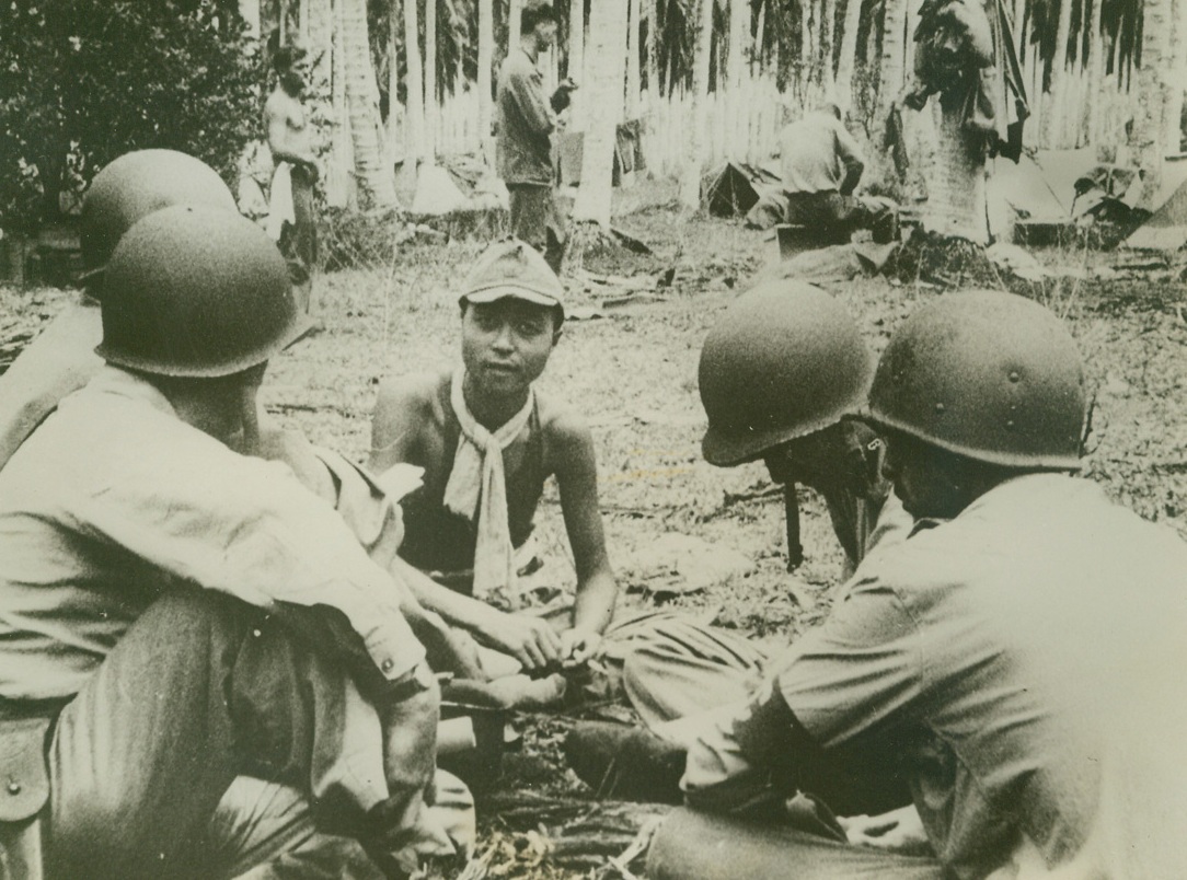 OFFICERS QUESTIONS JAP PRISONERS, 10/27/1942. GUADALCANAL, S. I.—Leisurely smoking a cigarette, a Jap prisoner answer the questions of four American officers, after a fierce battle on Guadalcanal in which American Marine and Air Corps personnel successfully halted an attempt to land reinforcements. Losses in ships and planes were heavy on both sides. Credit: U.S. Marine Corps photo from Acme;
