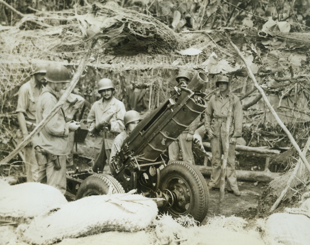 TROPICAL CAMOUFLAGE, 10/29/1942. GUADALCANAL—Under a camouflage to match the tropical setting, this crew mans a 75mm gun, one of the many that pour shells at the Japs that still remain on the island. Credit Line (ACME);