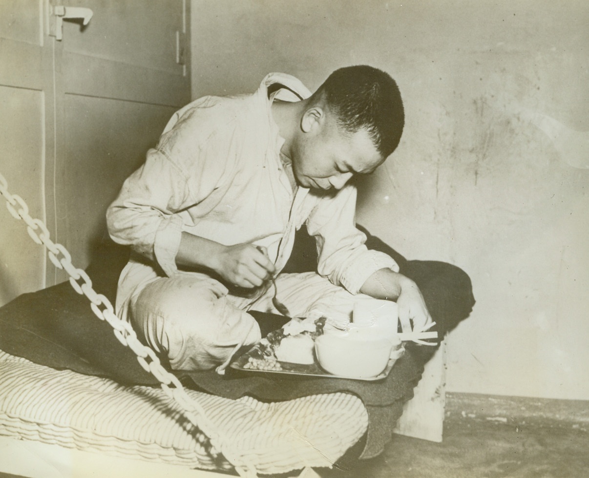 U.S. Takes Jap Prisoners in Aleutian Waters, 10/7/1942. Sitting in the traditional cross-legged fashion on his bunk, this Japanese prisoner wasted little time digging into a well-filled tray of U.S. Navy chow, including bread, potatoes and beans. The prisoner, one of the five taken after a Naval engagement in Aleutian waters, was confined to a ship’s brig pending transfer to shore. Credit: U.S. Navy Official photo from ACME;