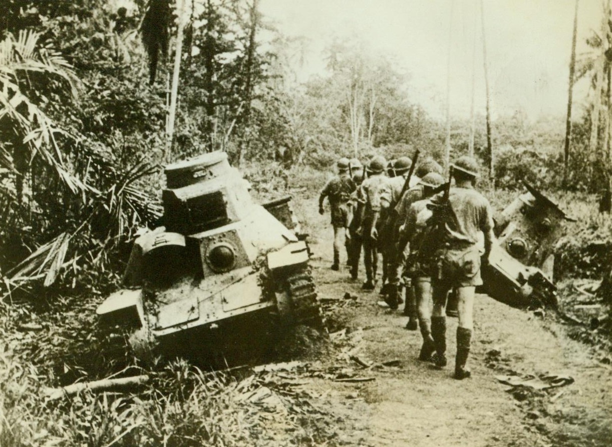 Left On The Roadside, 10/30/1942. Australia – Deserted when they were put out of commission during an unsuccessful Jap attack on Milne Bay, these Jap tanks lean dejectedly to the side of the road. Australian soldiers filing past them should smile with pride for they delivered a hard blow to the Nips in that battle  10/30/42 Credit Line (ACME);