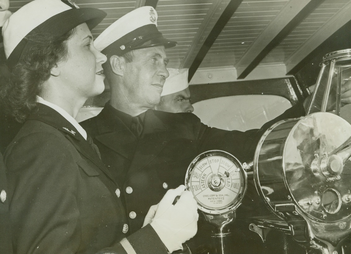A Wave Goes to Sea, 10/6/1942. Chicago -- Ensign Elizabeth Landis, new WAVE officer and niece of Judge Kenesaw L. Landis, tries her hand at running a Coast Guard cutter on Lake Michigan off Chicago, under the watchful eye of Chief Boatswain’s Mate Gustave Peterson. Credit: ACME;