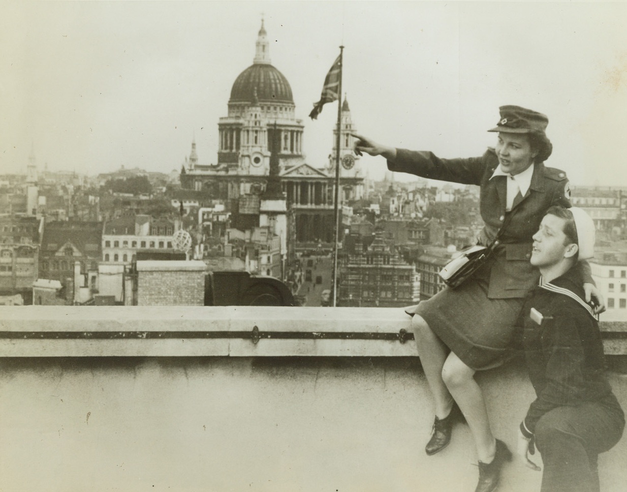 A Roof with a View, 10/2/1942. London – Whatever the American Red Cross worker is pointing out to the American sailor, it leaves him open-mouthed with interest, as they view London from the roof of the Daily Telegraph building on famed Fleet Street. St. Paul’s Cathedral is seen in the distance. Credit: ACME;