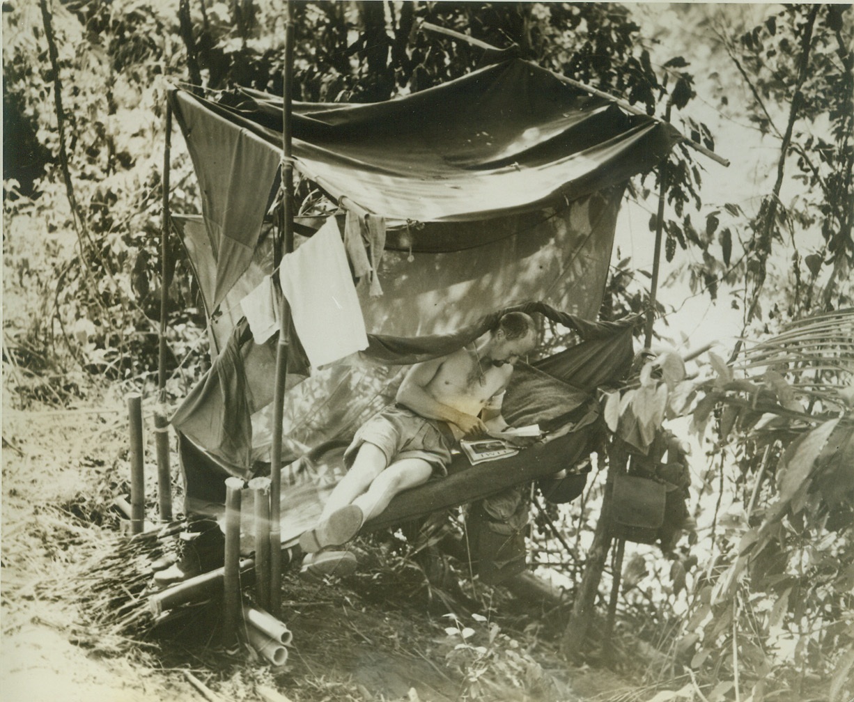 All the Comforts of Home, 11/12/1942. NEW GUINEA -- Americans love their comfort, and wherever they go they're bound to make themselves as comfortable as possible. Corp. Verl Parmee, a member of U.S. Infantry troops in New Guinea, relaxes and reads a letter from home on his unique bed, which he fashioned with bamboo poles.  Credit: (ACME);