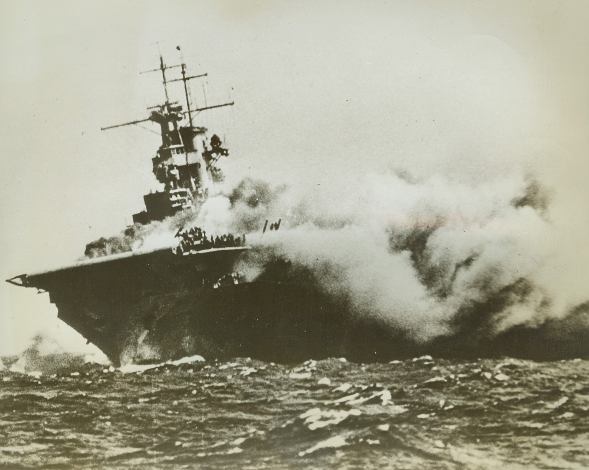 Wasp Crew Taking Refuge, 11/10/1942. This official U.S. Navy photo shows only a few members of the crew that remain on board on the forward flight deck.  They take refuge from the sweeping flames.  The 14,700-ton carrier was on escort duty near the Solomon Islands at the time she was attacked and sunk. Credit line (off. Navy photo from ACME);