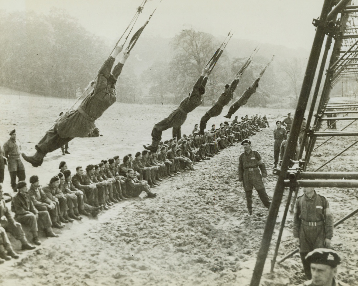 Paratroops Recieve Step-By-Step Training, 11/3/1942. These daring young men on a non-flying trapeze swing high and low and get the feel of the man on the landing end of a hurtling parachute. Other paratroop recruits await their turn on the multiple trapeze that is part of the airborne troops ground training. Credit: ACME.;