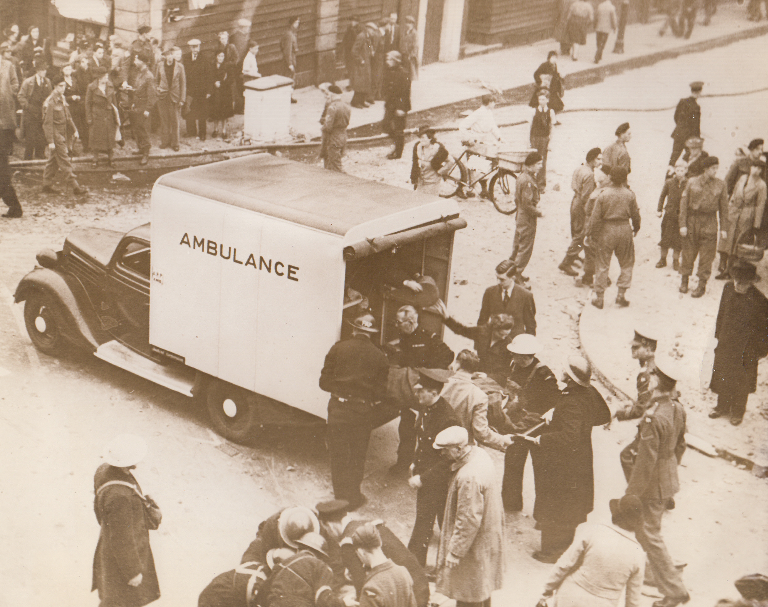 Casualties Being Removed After Raid, 11/4/1942. ENGLAND - Casualties are placed in an ambulance by ARP workers, after a Nazi plane had staged a daylight raid on a town in East Anglia. The plane damaged the office and shopping center of the town with bombs and machine-gunned the streets. Note fire house stretched across street, (upper part of photo).;
