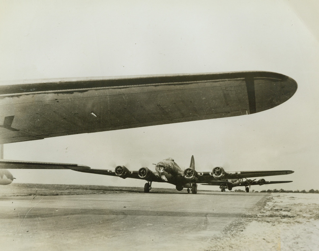 Roaring Off to Raid, 11/3/1942. England – While the wing and tail of one passes out of the picture, two of Uncle Sam’s “Flying Fortresses” are “getting up steam” on the runway just before taking off on a bombing mission over Germany or occupied France. The effectiveness of these monsters of America’s air armada is one point in the disputed field of aviation that stands without challenge. Passed by censor. Credit: Acme;