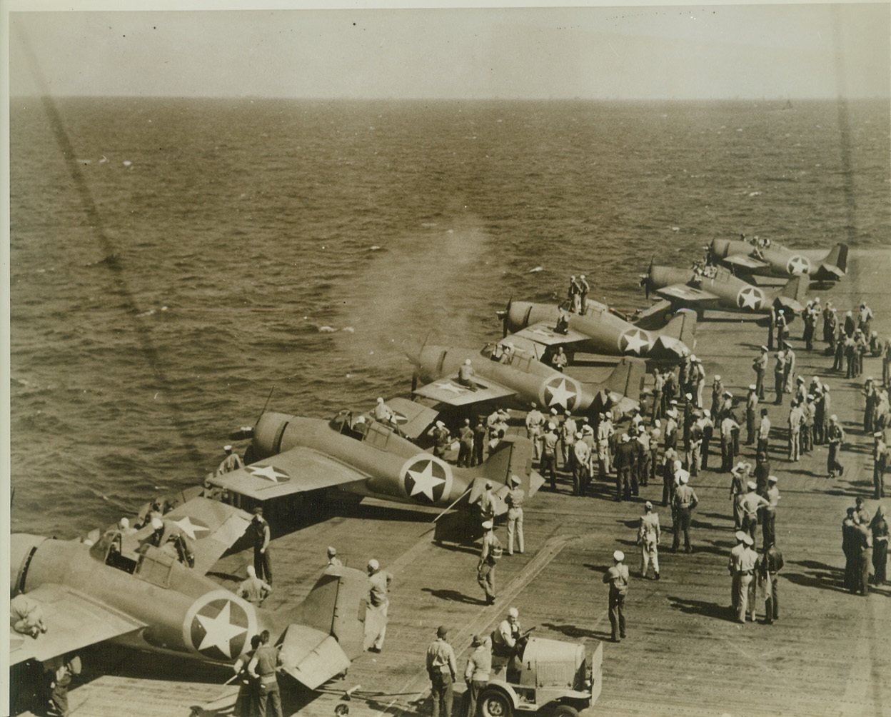 Getting Ready for North Africa, 12/29/1942. Six U.S. Navy fighter planes line up along the edge of the flight deck of an aircraft carrier to test their machine guns, as the warship nears the shore of North Africa. Smoke around nose of third fighter from left, shows its guns are in action. This photo has just been released in Washington. Credit: (U.S. Navy Photo from ACME);
