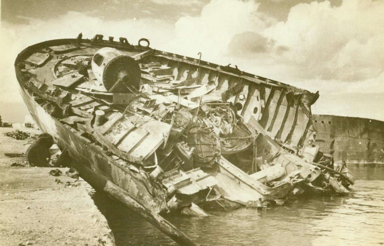 Beached With A Bounce, 12/27/1942. Benghasi – This Axis ship was actually blown clear out of the water of Benghasi Harbor, and now rests half on the pier while other enemy ships litter the bay. The British, who took over the Libyan port last month, are reported to have contacted units of Rommel’s depleted Army. 12/27/42 Credit Line (ACME);