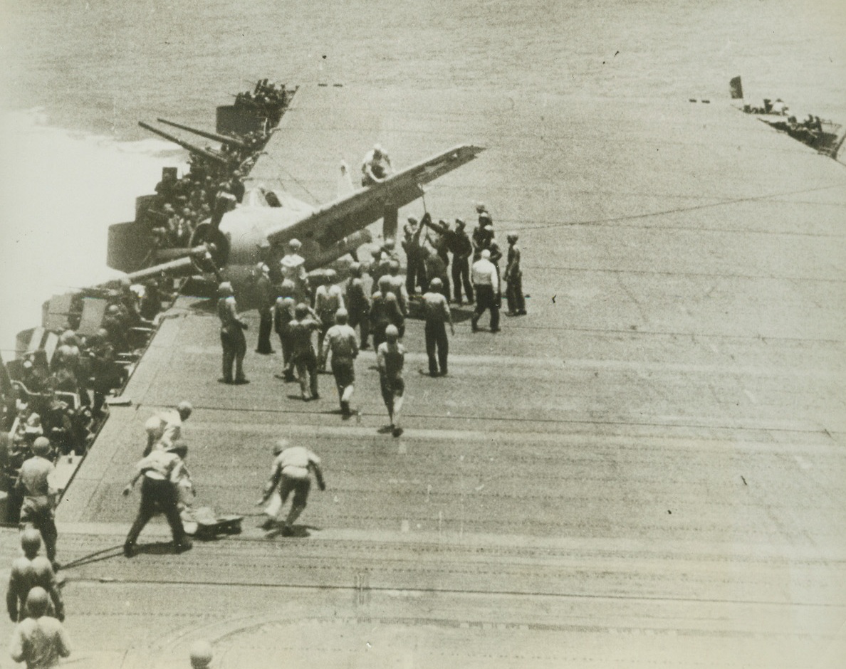 DEFY DEATH, 12/23/1942. Members of the U.S. carrier’s deck crew—some keeping their eyes on Jap planes overhead—run to the assistance of Navy plane which suffered an accident in landing during a battle in Pacific. Photo from a Navy film.Credit: OFFICIAL NAVY PHOTO-ACME.;