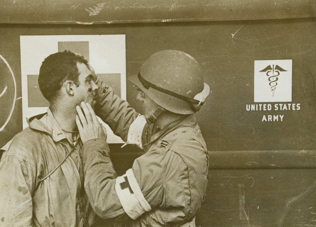 First Aid for Pilot, 12/11/1942. A U.S. Navy ensign receives medical attention from a U.S. Army ambulance surgeon at Safi, French Morocco, after he landed his SBD (Douglas scout bomber) in the water one mile from the beach.  His plane had run out of gas.  He rowed his rubber boat ashore and walked 40 miles to the base.  This photo, taken during the occupation of the North African coast by Anglo-American forces, has just been released in New York. Credit line (ACME);