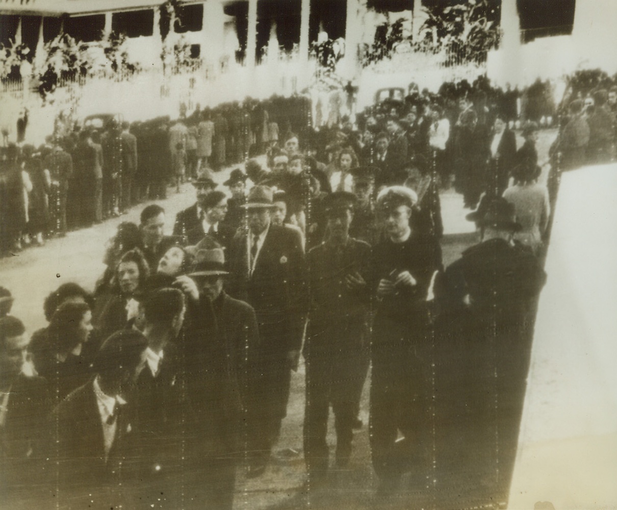 Paying Last Respects to Dablan, 12/28/1942. Algiers—Closely packed civilians file past the bier where Admiral Jean Francois Dablan lies in state, in Algiers. The slain French chief might have caused mistrust in some parts of the world, but this photo is testimony that he was popular in French Colonial America. His bier may be seen in the distant background between the double-lines of visitors. Credit: ACME radiophoto;