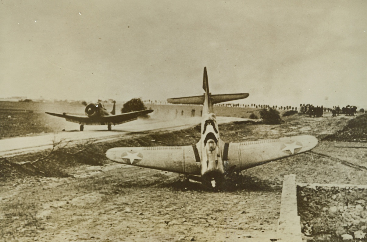 Yank Plane Takes Off (part of title illegible), 12/11/1942. A U.S. Navy dive bomber takes off from a road near the Safi, French Morocco airport, while another is shown nosed over (foreground). This photo, taken during the occupation of North Africa by Anglo-American forces, was released in New York today. (Passed by censors). Credit: ACME.;