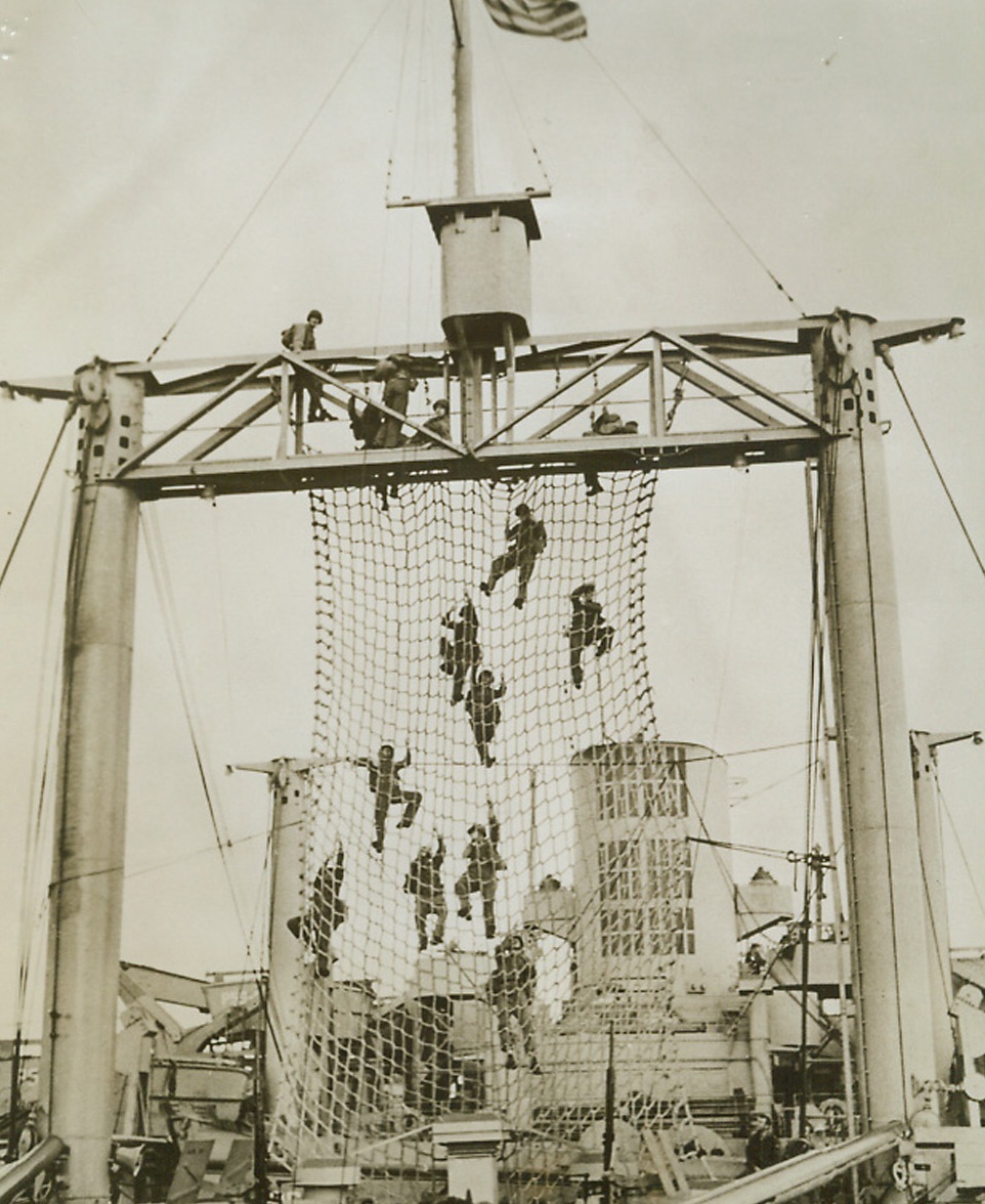 Practice Commando Tactics at Sea, 12/21/1942. At Sea—US Fighting men practice commando tactics on a ship under way at sea. A net is suspended from a ship boom so that the men can learn how to transfer into barges in actual operations. They carry all the equipment they would normally have in an actual landing.  Credit: ACME.;