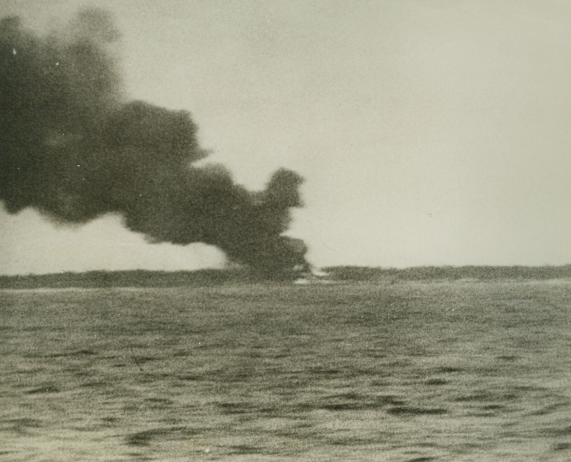As U.S. Navy Struck Back, 2/14/1942. With the Pacific Fleet – Smoke rises from Wotje Atoll, one of the Marshall and Gilbert island group in the Western Pacific, testifying to the marksmanship of gunners and bombers who took part in the U.S. Navy’s first powerful counter-blow at Japanese territory.  Damage on Wotje included the firing of hangars, fuel stores and munition dumps, and the sinking of a number of vessels anchored offshore.  This picture, among the first of the Pacific success, was made from aboard one of the attacking cruisers.Credit Line: Pathe Newsreel (from ACME);