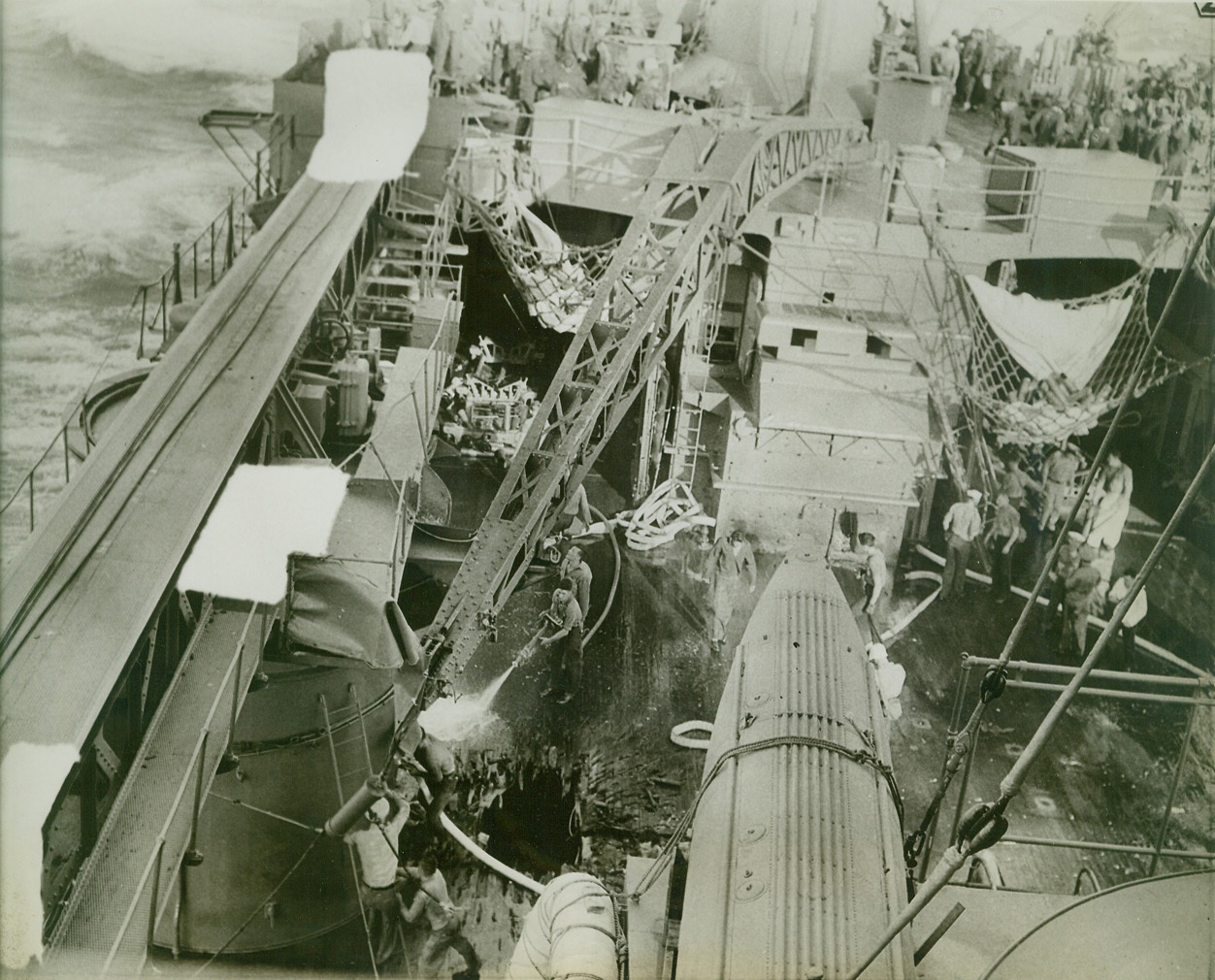 First Pictures Show Bomb Damage to U.S. in Jap Attack, 2/15/1942. San Francisco—In one of the first pictures to arrive in the United States following the Navy’s daring blasting of Japanese bases in the Pacific, bomb damage to one of the Pacific fleet’s units is shown here. A seller plays a stream of water from a hose on the hole in the deck as the damage control party swings into action to stop a fire from a Jap hit. Credit: ACME.;