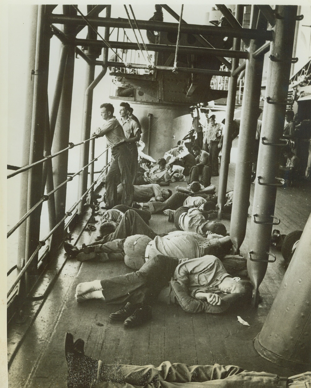 Sailors Sleep After Day of Battle, 2/18/1942. SOMEWHERE IN THE PACIFIC -- Sailors as they slept with heads pillowed on life jackets, on the deck of a unit of the U.S. Fleet, the day after the United States Navy had attacked the mandated Gilbert and Marshall Islands. Note another group of sailors standing watch as vessel traveled through sub-infested waters.   Credit: (ACME);