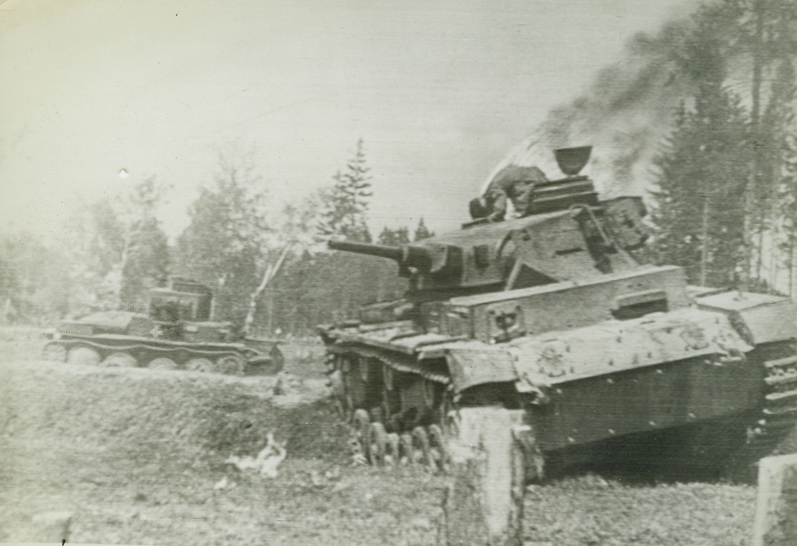 “March of Time”, 2/11/1942. From film record of one day of war on Russian fronts, filmed by 160 Russian cameramen, 39 of whom died in action, came this battlefield scene as a German tankman turns attempting escape from tank at right; another filled with dead at the left.Credit: ACME Telephoto;