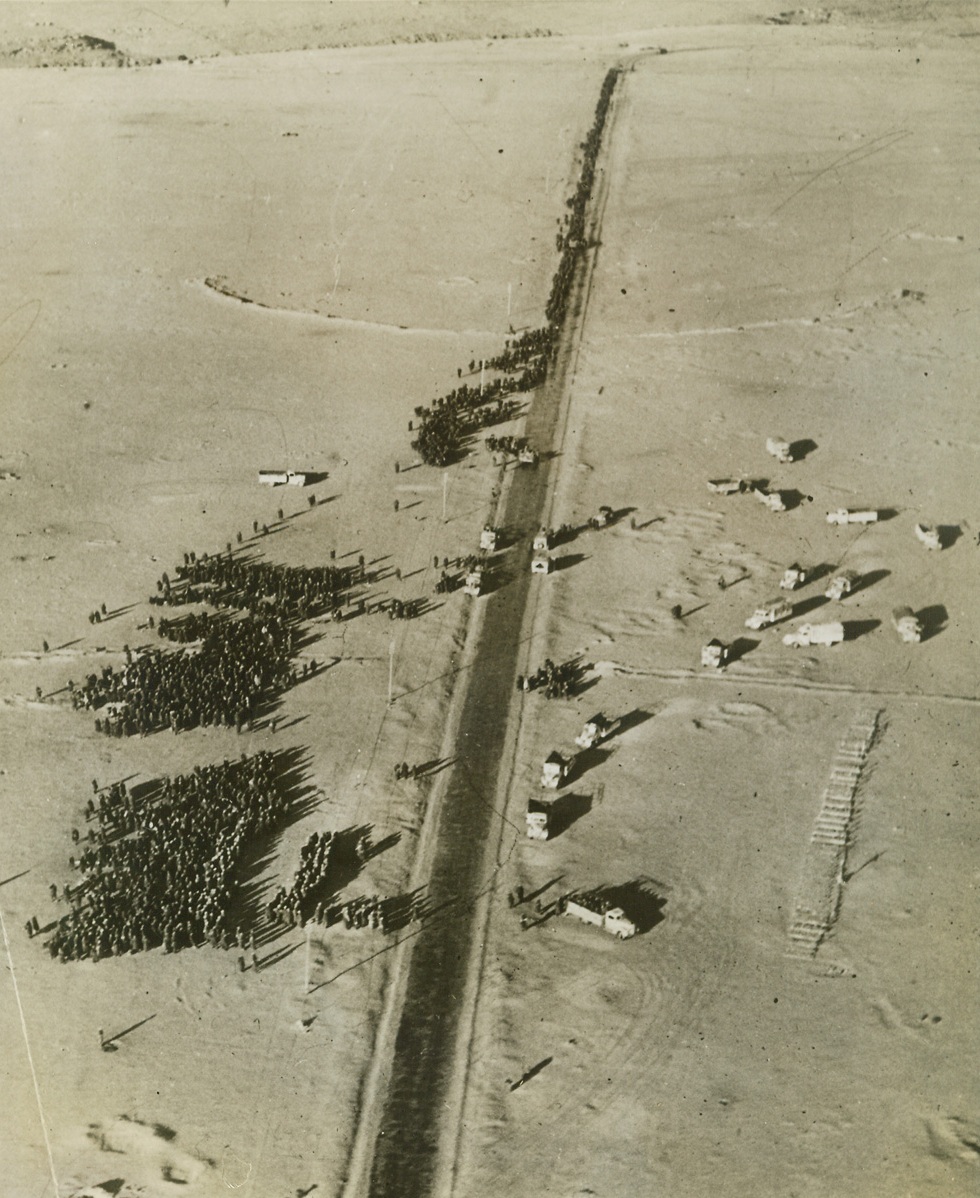 Oft-Repeated Scene in Desert, 2/2/1942. Bardia, Libya – Overtaken by mechanized South African troops in the Western Desert, German and Italian defenders of Bardia are herded together for transportation to a prison camp.  It was the second time the Allies had captured the Libyan city, having been driven out after their first desert offensive.  Credit line (ACME);