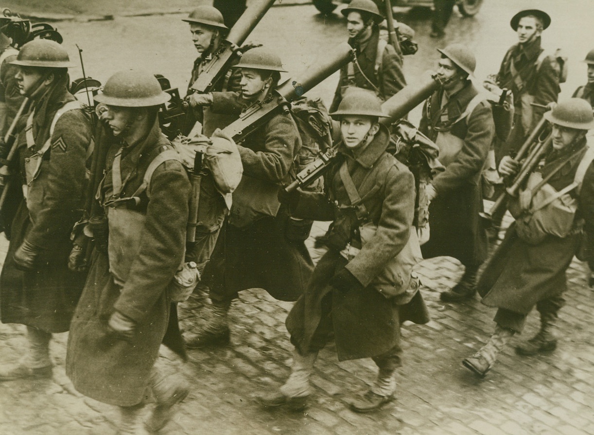 U.S. Troops Come Prepared, 2/8/1942. Ulster, Northern Ireland - Carrying Machine Guns over their shoulders, U.S. soldiers of the First Expeditionary Force to land in the British Isles march down a street in an unnamed Ulster town toward their camp after debarking. Passed by censors and flown to the U.S. by Clipper. Credit: ACME;
