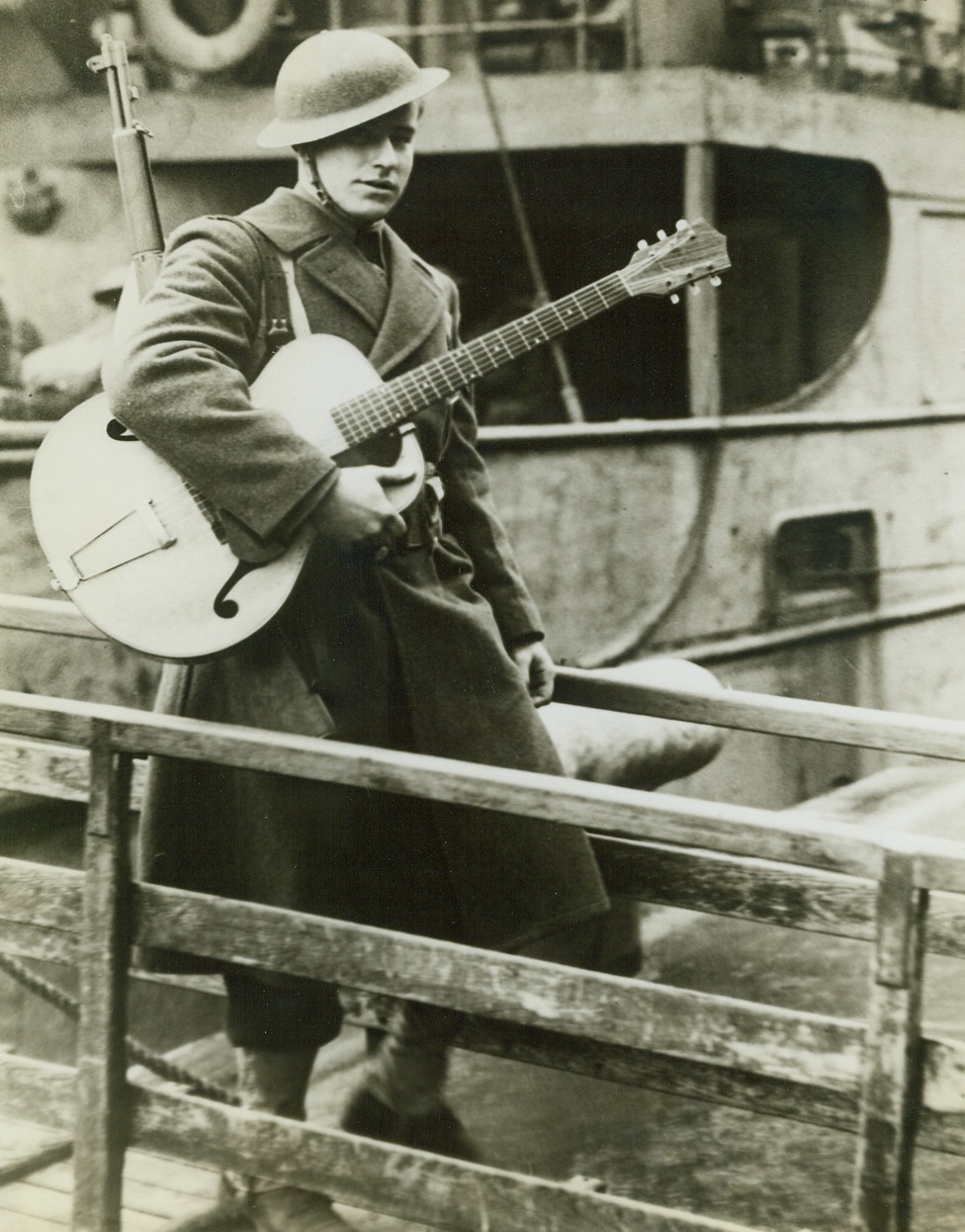 Takes His Music to Ireland, 2/8/1942. Northern Ireland - Pvt. Roy A. Brown, of Waterloo, Iowa, took his guitar along when he went to Northern Ireland with the first contingent of U.S. soldiers to set foot in the British Isles during World War II, and he carries it tenderly as he leaves the transport which brought him and his mates across the sub-infested Atlantic. Passed by Censors. Credit: ACME;