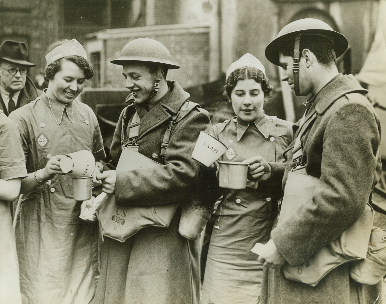 British Girls Pour Tea For Yanks, 2/8/1942. A Northern Irish Port - Girls of the NAAFI, as they poured tea for soldiers of the American Expeditionary Force, recently arrived in Northern Ireland.;
