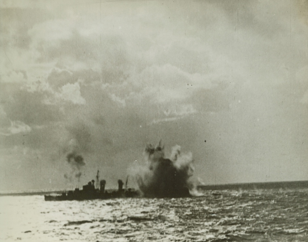 A MISS IS AS GOOD AS A MILE!, 3/19/1942. SOMEWHERE IN THE MEDITERRANEAN—An aerial bomb as it exploded just short of the stern of a British destroyer, protecting a convoy bound for Malta. But—“a miss is as good as a mile,” and the craft’s anti-aircraft guns can be seen firing at the raiding planes from the forward part of the destroyer. Credit: Movietone News photo from Acme;