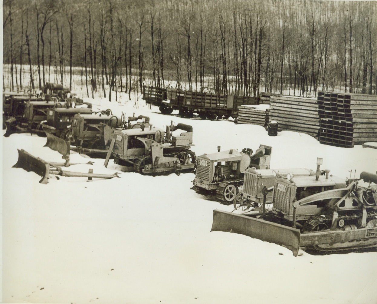 DEFENSE MATERIAL BEING WASTED BY CCC, 3/9/1942. Valuable and vital defense material is being wasted and wrecked by the Federal Civilian Conservation Corps in the abandonment of some of its camps in Pennsylvania, according to a copyrighted story in the Philadelphia “Inquirer,” March 8. While the war production board is attempting to utilize all “surplus war materials,” CCC storehouses are loaded to the ceiling with brand-new tools, the story states, and in spite of the dwindling civilian supply of all-wool clothes, brand-new, unpacked supplies of long underwear, uniforms, oilskin raincoats, rubber overshoes and even army blankets have been burned by the CCC. While Price Administrator Leon Henderson has announced it might be necessary to requisition tires from private owners for use of the armed forces, there is one CCC storehouse packed with at least 1200 good truck tires, some of them virtually new. While autos and trucks are being rationed, the CCC is permitting usable trucks to rust and rot in open fields, unprotected from severe winter weather. While there is a shortage of road equipment, graders and caterpillar tractors are wasting away in the same manner. This story was written about only certain camps in Pennsylvania – and there have been camps in 47 other states, many of which have been closed down. NEW YORK BUREAU These tractors left to rust in the snow of an open field might be doing their bit for national defense. Credit: ACME;