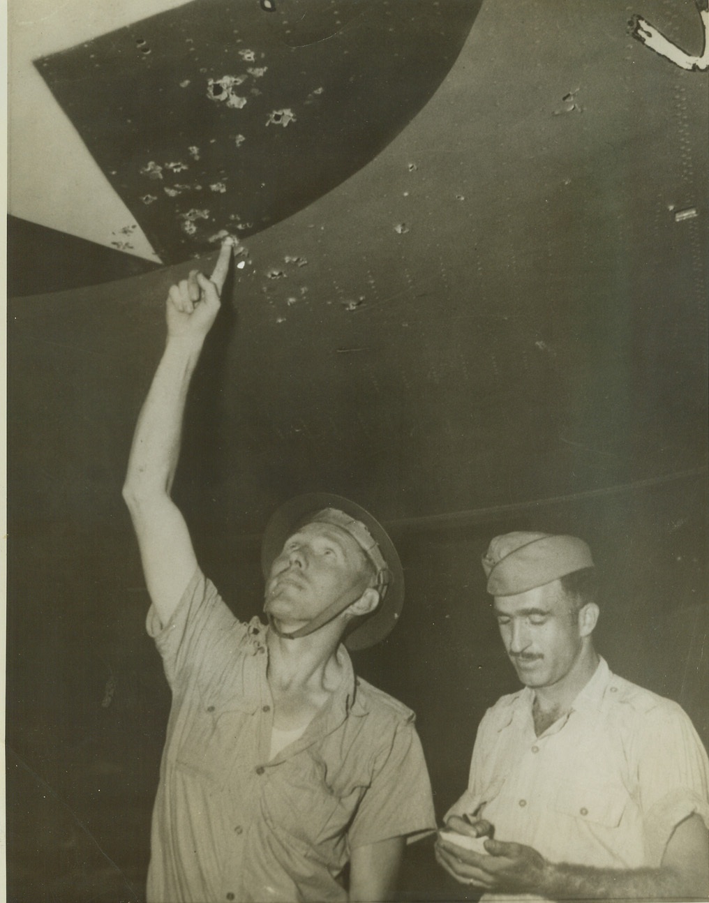 U.S. FLIERS WHO AID “AUSSIES” INSPECT DAMAGE TO THEIR SHIP, 3/9/1942. In one of the first pictures from Australia since the United States entered World War II, two U.S. Army “Flying Fortress” crew members examine the wing of their ship which was struck “a few times” by Jap bullets during a tiff with the invaders in the South Pacific. Now in Australia to bolster the Allied Forces, this was one of the “Flying Fortresses” to see action against the Japanese in the Philippine area. Credit: ACME;