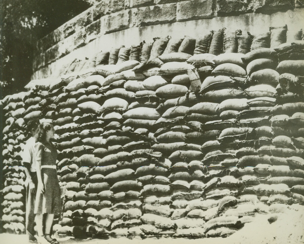Reinforcement for an Already Strong Shelter, 3/13/1942. Sydney, Australia – On Sydney’s home front, preparations proceed apace for expected aerial invasion tries, with sandbags reinforcing already strong shelters.  ‘Professionals’ have erected this sandbag for around a shelter which will accommodate 50 people in its two rooms.  The cost was 100 pounds, a little less than $500.  This is just one of the many fortified homes and offices in Sydney. Credit line (ACME);