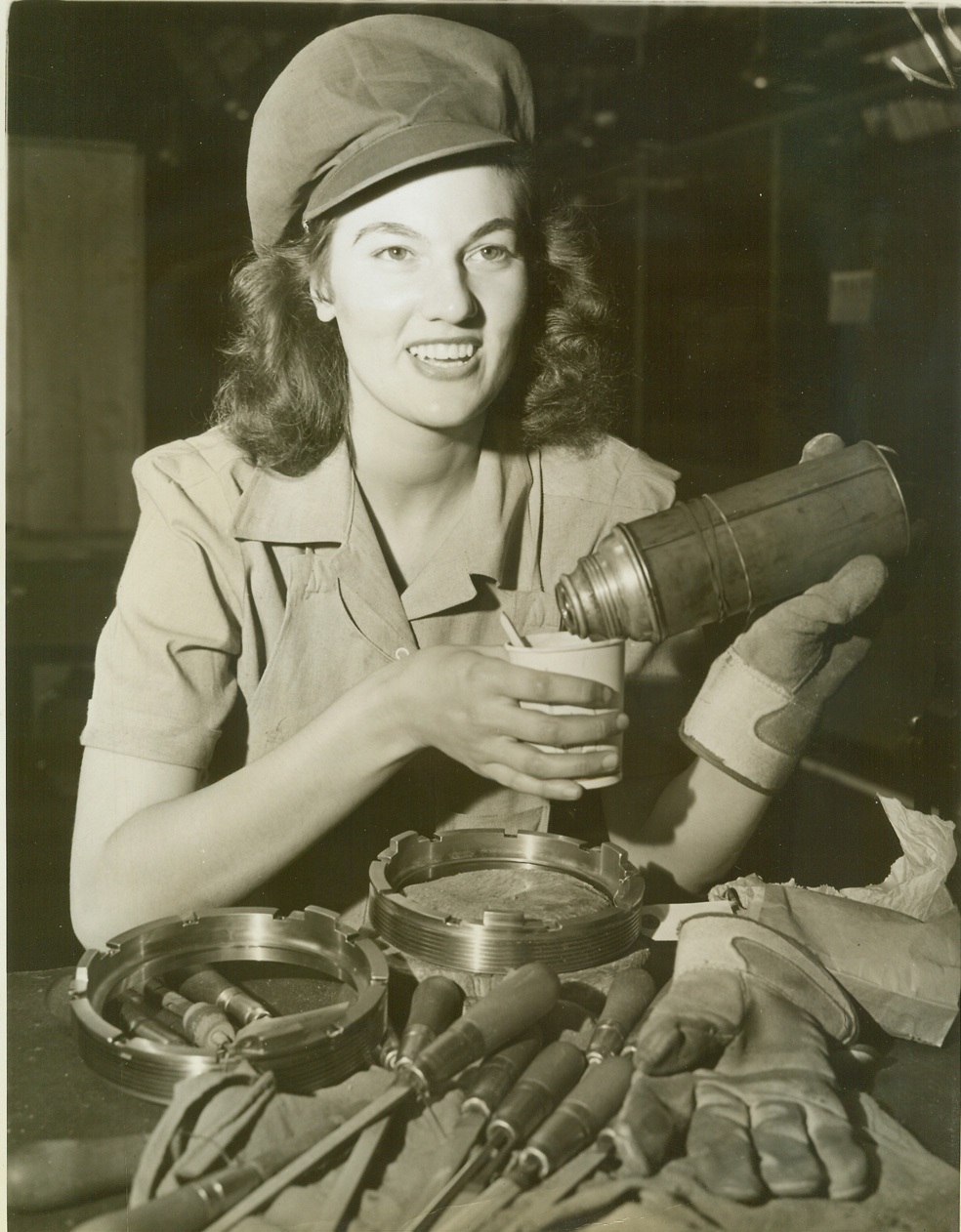 WOMEN ENTER ANOTHER WAR INDUSTRY, 4/17/1943. The women of America are plunging more and more whole-heartedly into America’s tremendous war production effort. With husbands, brothers and sweethearts in the Armed Forces, modern women are doing their patriotic bit in the nation’s factories, as well as in uniformed services. The uniform for them is overalls or slacks, and many have left clean, leisurely office jobs for positions as inspectors, equipment handlers or actual machine jobs. In this New Jersey propeller factory an initial group of 14 women began work Jan. 29, 1942, after a six-weeks vocational school course, and the feminine element is appearing in ever-increasing numbers among workers fashioning the blades that will drive the war planes which will drive the Axis from the skies. This series shows some of the “bladeswomen” at their work. Time out for lunch amid an atmosphere of tools and gloves. A far cry from metropolitan tea rooms many of the workers formerly frequented. Credit: OWI Radiophoto from ACME;