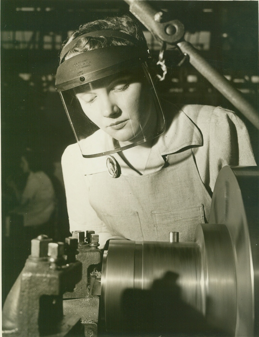 WOMEN ENTER ANOTHER WAR INDUSTRY, 4/17/1942. The women of America are plunging more and more whole-heartedly into America’s tremendous war production effort. With husbands, brothers and sweethearts in the Armed Forces, modern women are doing their patriotic bit in the nation’s factories, as well as in uniformed services. The uniform for them is overalls or slacks, and many have left clean, leisurely office jobs for positions as inspectors, equipment handlers or actual machine jobs. In this New Jersey propeller factory as initial group of 14 women began work Jan. 29, 1942, after a six-weeks vocational school course, and the feminine element is appearing in ever-increasing numbers among workers fashioning the blades that will drive the war planes which will drive the Axis from the skies. This series shows some of the “bladeswomen” at their work. Rose Walker, a married woman who used to be an office worker, now operates a lathe on the nut line. Credit: OWI Radiophoto from ACME;