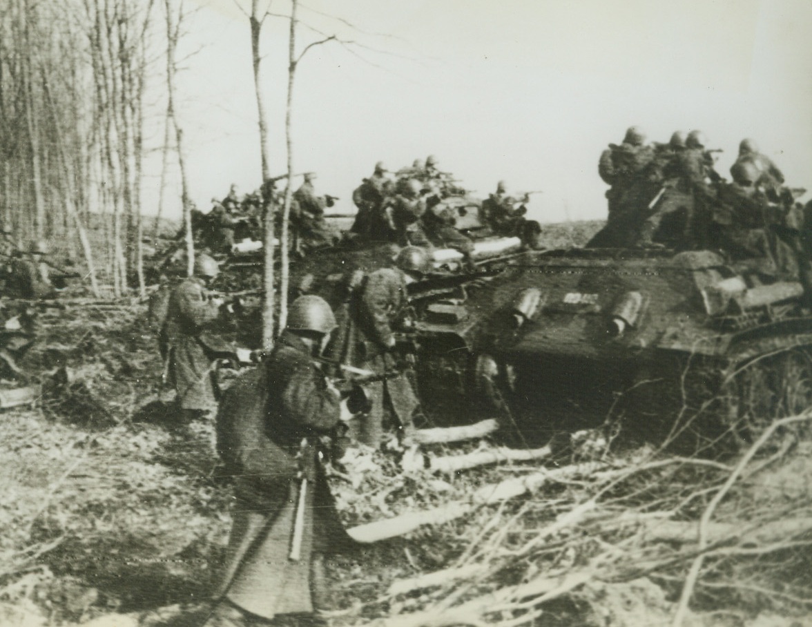 Routing Germans in Kharkov Region, 5/18/1942. RUSSIA—Tanks provide good cover for advancing Red Army troops who, when they arrive at the agreed strategic rendezvous, take up close firing positions on and behind the tanks from where they direct a withering fusillade on lingering outposts. Here, in this picture just received, Red Army units are dislodging Germans in the Kharkov area. Passed by censors.Credit: ACME;