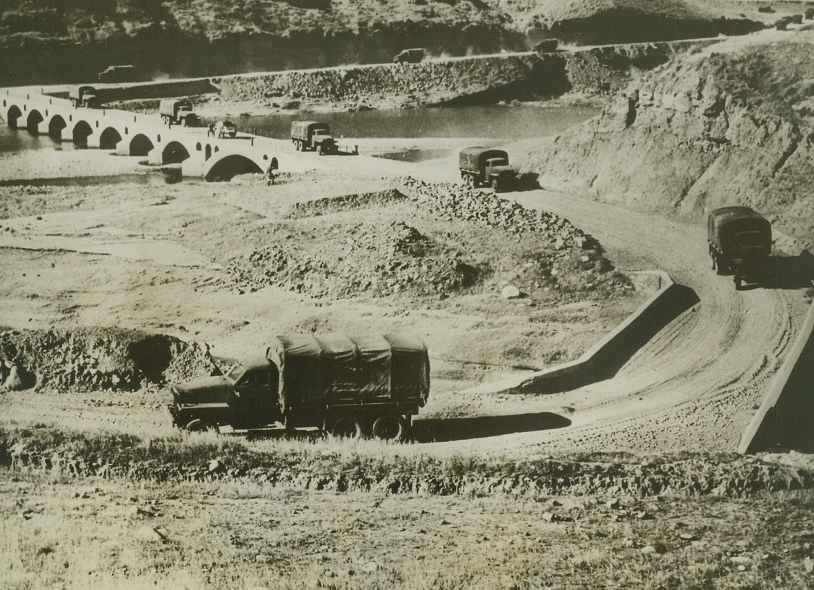 Supplies for Russia Sent Via Persian Gulf, 6/9/1942. SOMEWHERE IN IRAN—Allied war supplies are pouring into Russia in ever increasing quantities, via Bandar Shahpor and the Trans-Iranian Railway. Transported across salt marsh and desert to Ahwaz, road and rail convoys there join the flow of supplies proceeding up river from Kharramshah and Bushire, all thence continuing northwards to the U.S.S.R. Here, a long truck convoy carrying supplies for Russia, crosses a stream “somewhere in Iran.” Passed by censors.Credit: ACME;