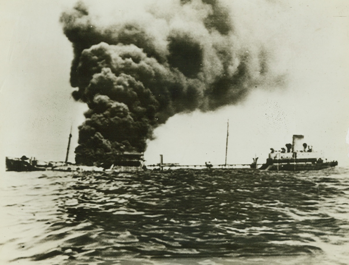 Tanker Ablaze After Axis Sub Attack, 6/9/1942. This unusual photo was taken by a member of the crew of this blazing United States tanker as he and other crew members raced for their lives away from the sides of the vessel to escape a fiery death. The photo was made last April, when the tanker was torpedoed and shelled off the coast of South America. The ship sank shortly after the photo was taken. Passed by censor. Credit: ACME;