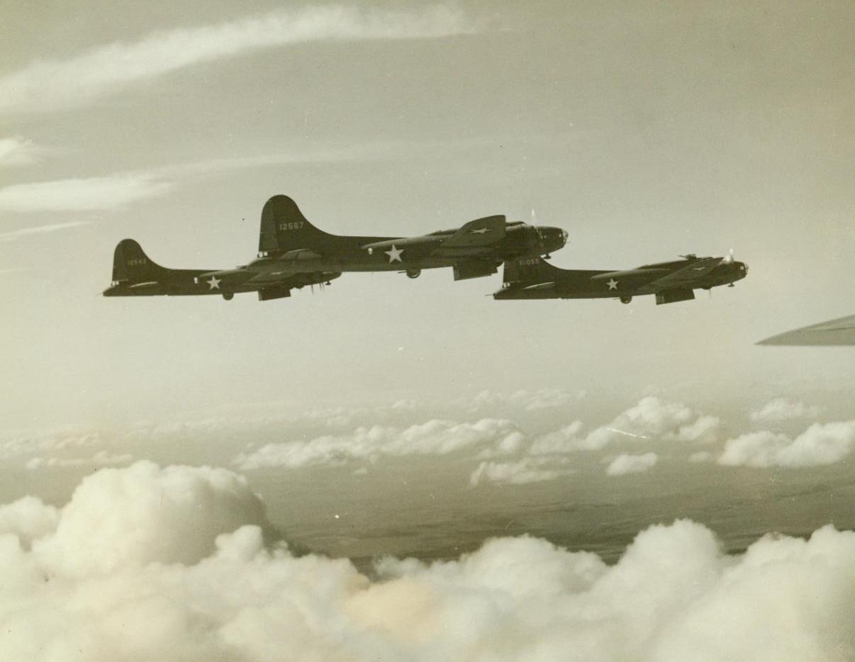 Objective Ahead, 7/26/1942. When the bombardier of a Boeing flying fortress sights the target, he swings open the bomb bay doors. This formation, walking its way over fleedy clouds on a practice run at an operational bombing base somewhere in the Northwest, is ready for business 7/26/42 (ACME);