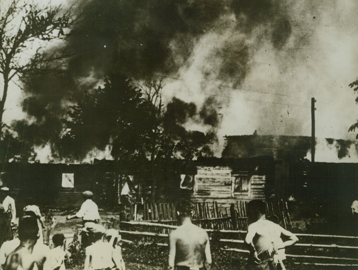 Nazi Handiwork, 8/3/1942. RUSSIA—This photograph, found on German Lance Corporal Ludwig Lehr, taken prisoner on the Kalinin front, shows Nazi soldiers, stripped to the waist, as they watch hungry flames consume a Russian village which they fired.Credit: ACME;