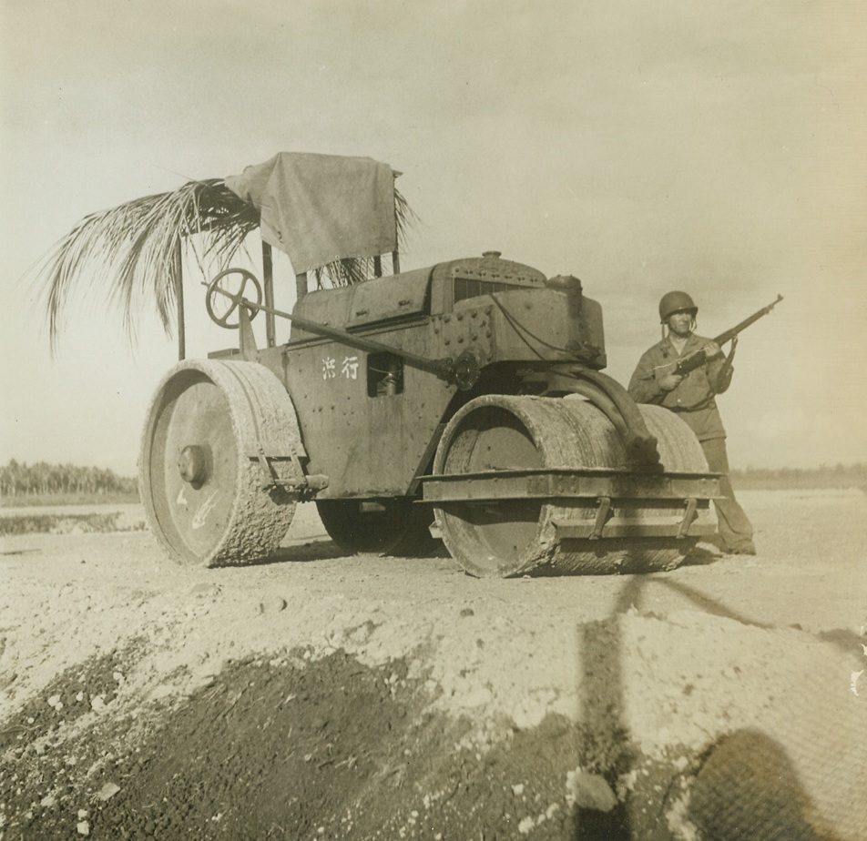Jap Steam-roller in Enforced Idleness, 8/30/1942. Solomon Islands – A U.S. Marine stands guard over a Jap steam-roller which smoothed the ground on Guadalcanal island for a Jap air field until the Leathernecks took over the island in their offensive in the Solomons.  Photo, relased in Washington yesterday, was made by War correspondent photographer Sherman Montrose of ACME News pictures. Credit line (ACME);
