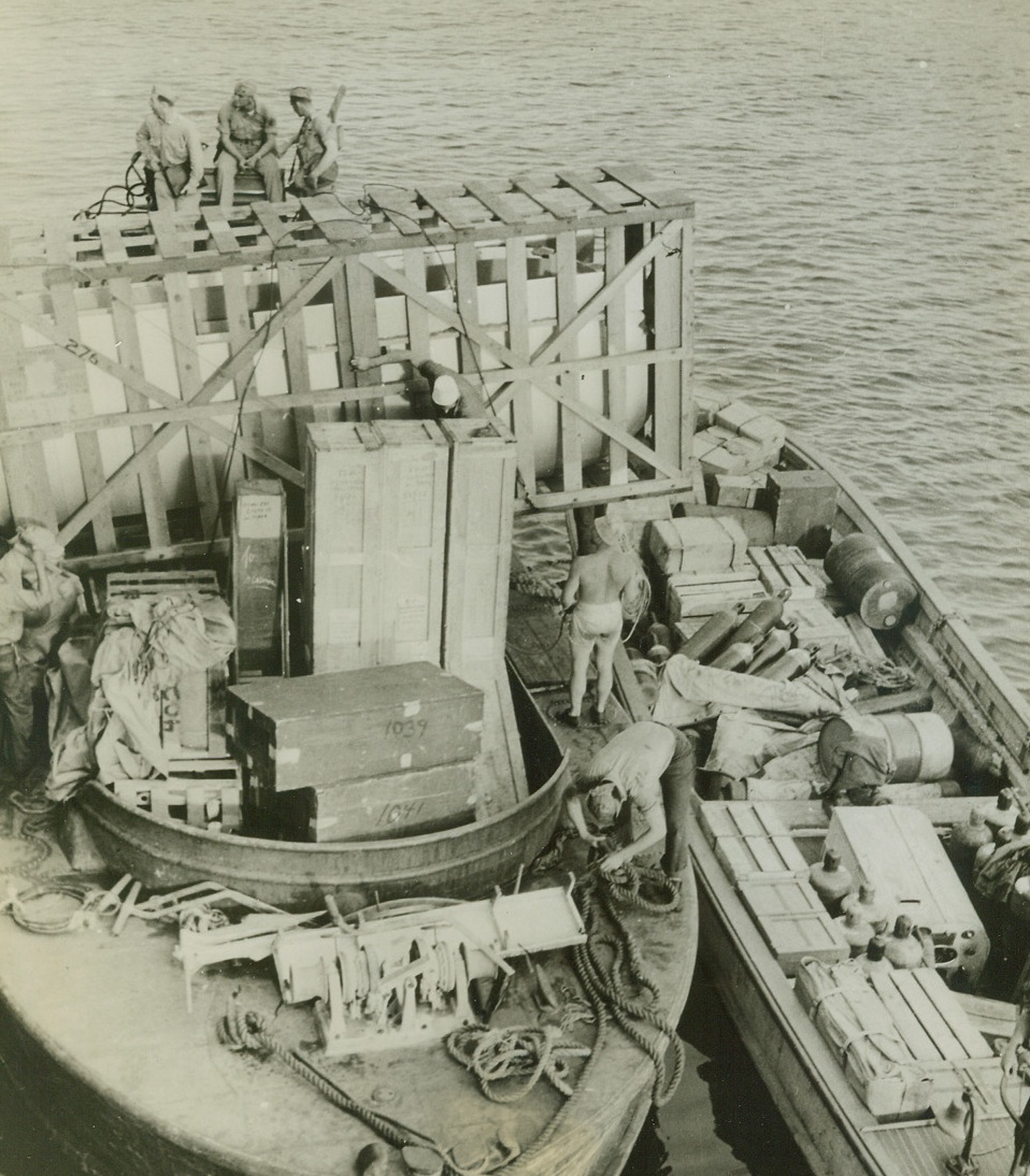 Supplies Help Form Pacific ‘Ring of Steel’, 8/13/1942. Two lighters drawn up beside a cargo boat are loaded with tools and supplies for one of the U.S. built bases in the Southwest Pacific as a ‘Ring of Steel’ is formed against the Japs . Credit line (ACME);