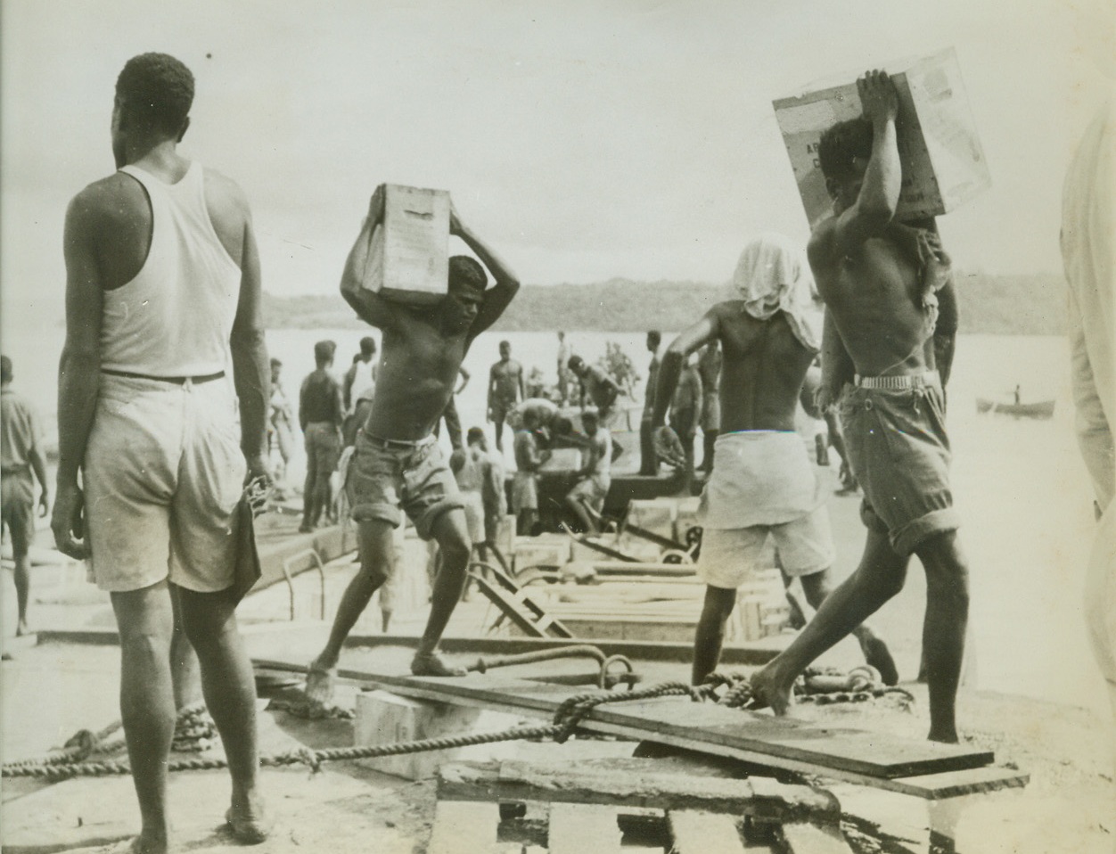 Natives Unload Supplies for Pacific Base, 8/13/1942. Natives of an island in the Southwest Pacific unload supplies brought ashore by a lighter for a U.S. operations base which will be used to prevent further Japanese conquests in the area.  Credit line (ACME);